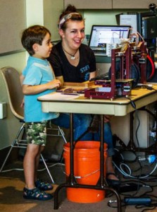 A staff member helps a boy to 3D print.
